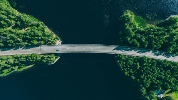 Aerial view of bridge road through blue lakes with green woods in Finland.